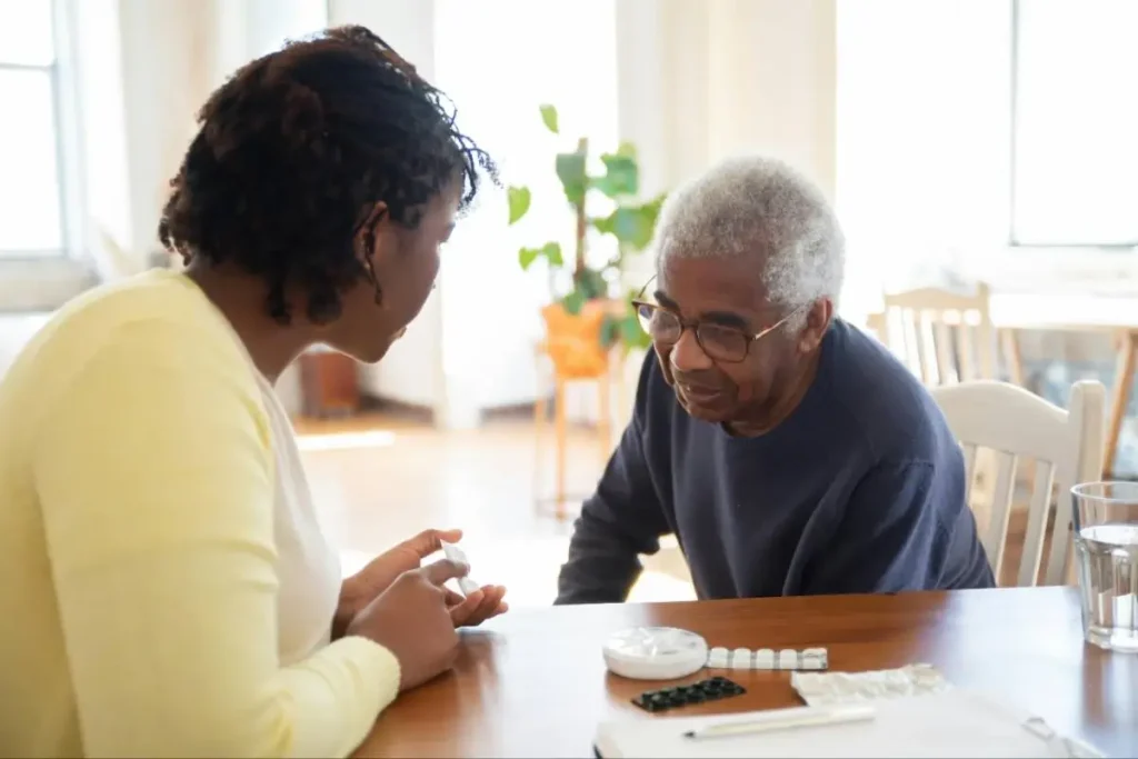 Woman helping an elderly man at a table